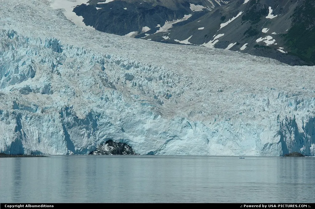 A lonely fisherman looks insignificant against the huge towering face of the Aialik Gla...